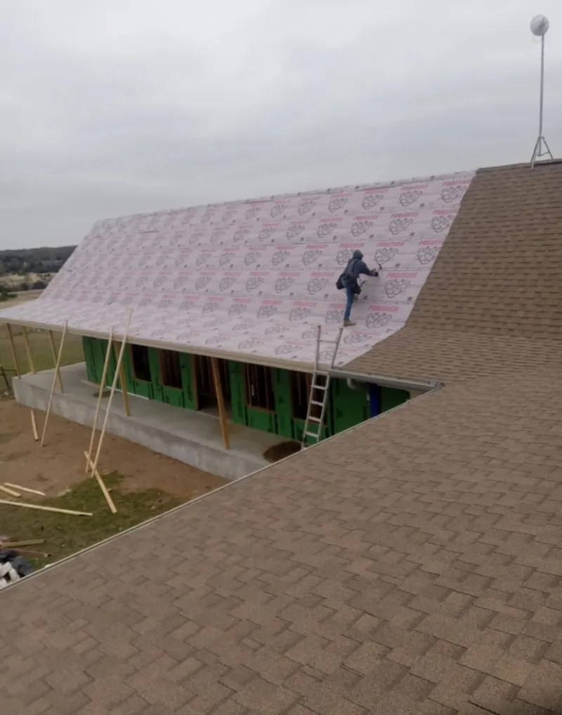Worker preparing underlayment for a metal roof installation in Newberg